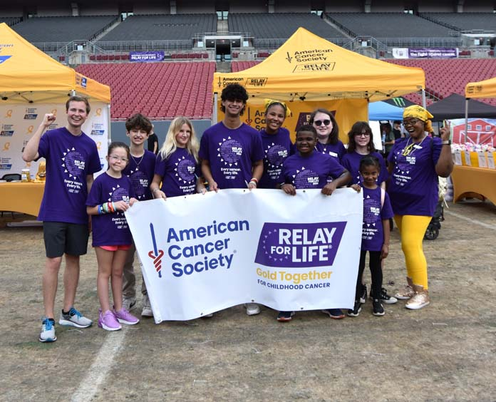 group of children holding Gold Together banner while walking on track