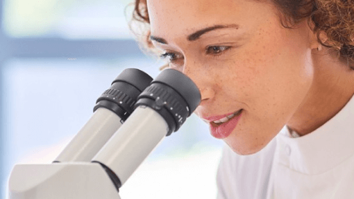 female researcher looking at microscope