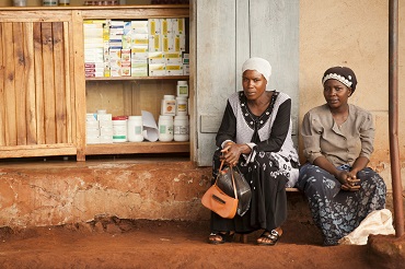 Two Women Sitting on Dirt Road in Unknown Country