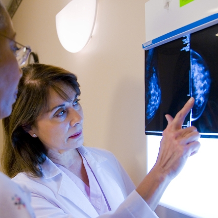 A female doctor examines a mammogram x-ray with her patient in a hospital setting.