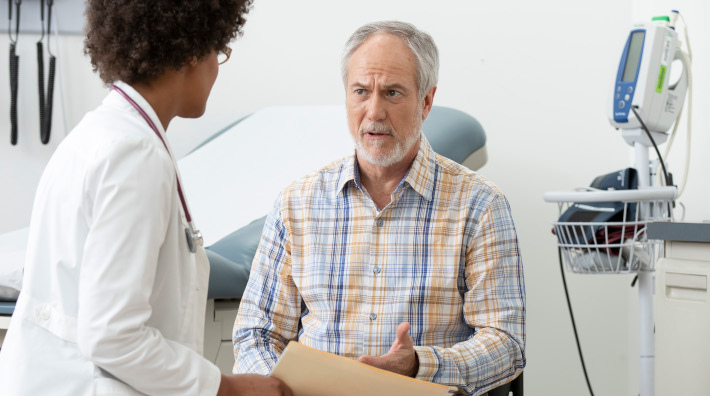 concerned man talking to his doctor in an exam room