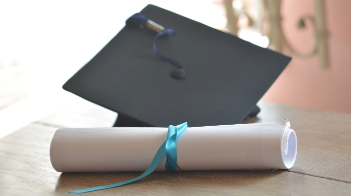 Black mortarboard with blue tassel and diploma