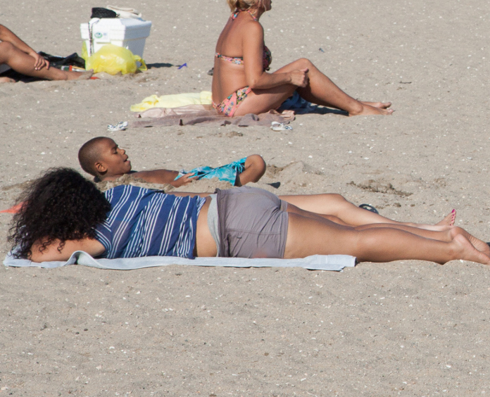 woman and her son lay in sun on a crowded beach