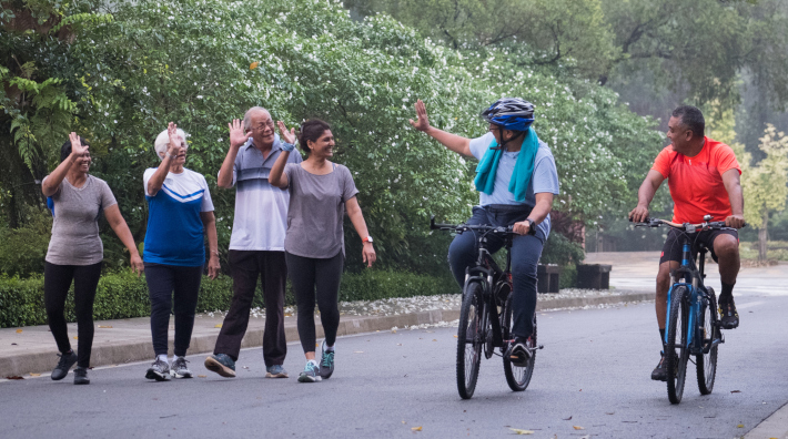 A group of active seniors in the park greet each other as they pass on their morning walk and bike ride