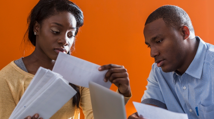 worried couple sort through paperwork at desk