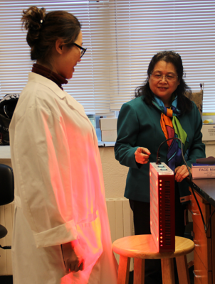 Dr. Mei Wu's research fellow stands in front of the low-level laser they’re testing as light therapy to ease intestinal side effects during certain types of chemotherapy. 