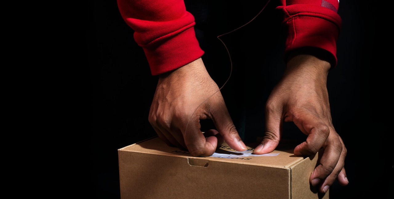 Hands pressing label on box red sweatshirt sleeves