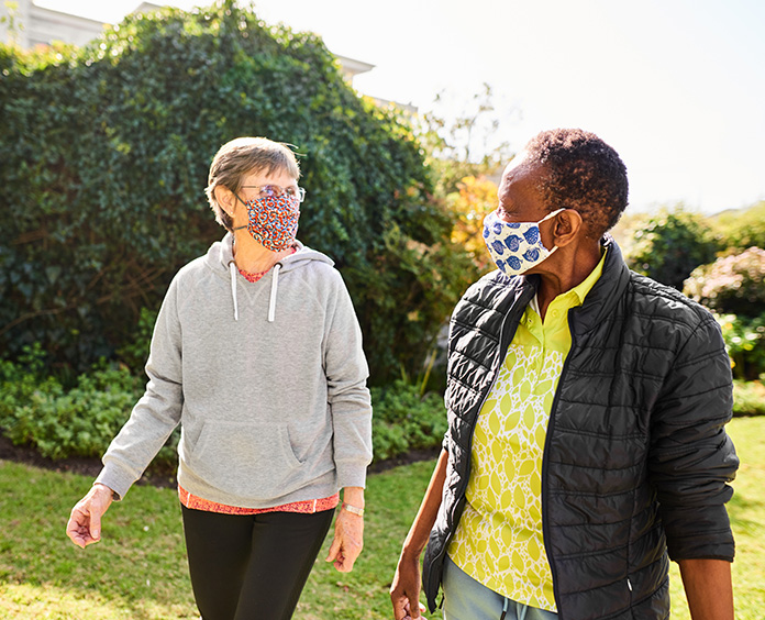 white and black woman walking outside wearing COVID masks