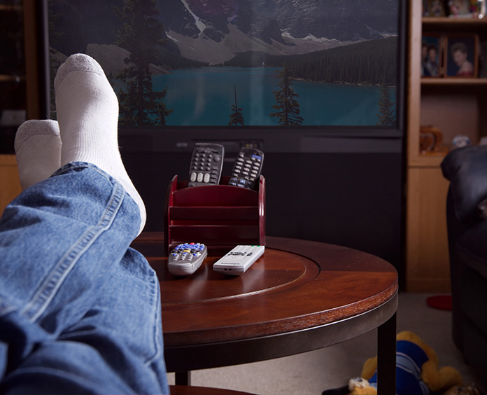 socked feet on round coffee table with multiple remotes