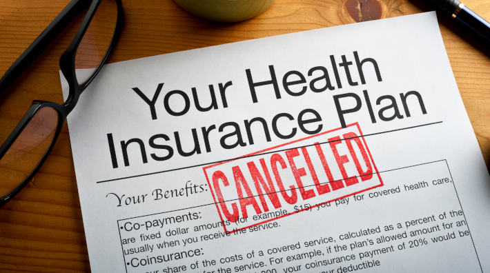 close up of health insurance plan with the word "Cancelled" stamped on it in red