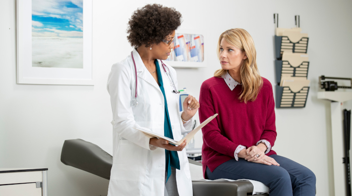 female doctor speaking with female patient in exam room