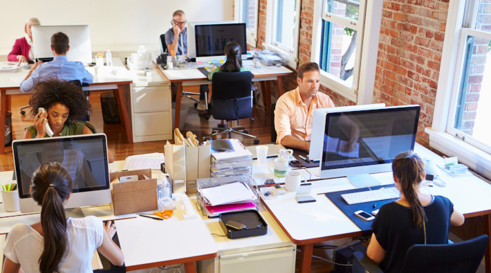 Wide Angle View Of Busy Design Office With Workers At Desks.
