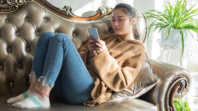 young woman sitting on a couch looking at her phone