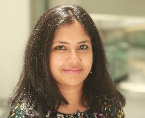 white woman with curly brown hair, longer than shoulders, smiling with teeth showing