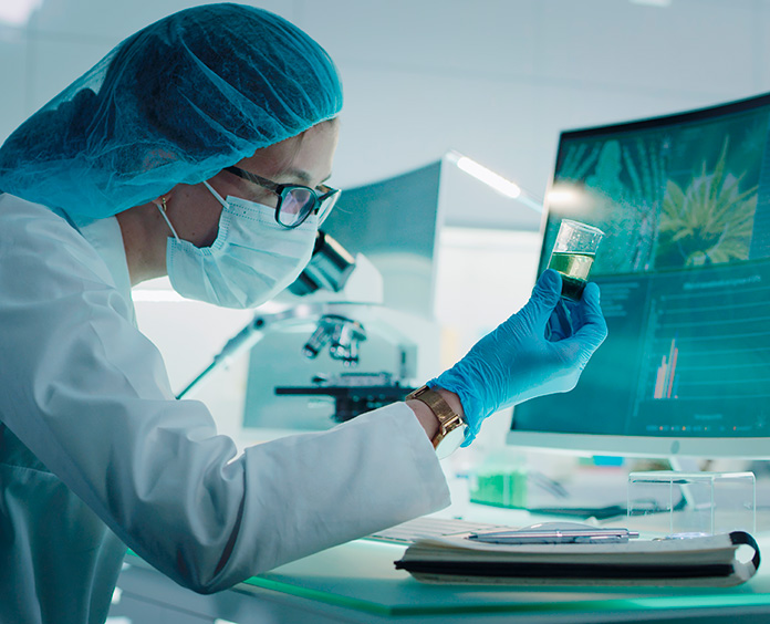 Researcher in front of computer holding something with liquid